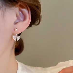 Elegant silver bow pendant earrings with white zircon crystals shown on a model