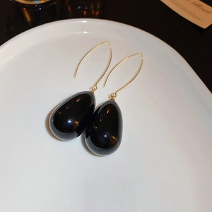 Vue macro de boucles d'oreilles pendantes noires polies sur assiette en porcelaine