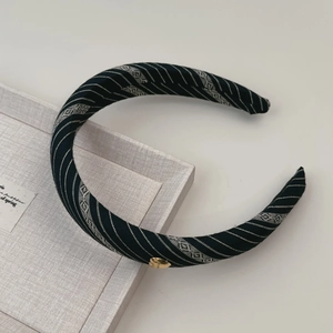 Détail d'un serre-tête en tissu rayé vintage avec boucle métallique dorée en forme de cœur