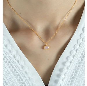 Close-up of a pink oval gemstone pendant on a gold titanium steel chain worn by a model
