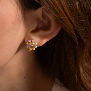 Détail macro d'une boucle d'oreille en acier doré 18K avec diamant central et perles