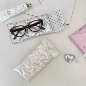 Macro detail of quilted PU leather bow glasses cases in silver and white finishes