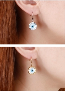 Détail des boucles d'oreilles œil protecteur en or et argent avec perles en verre