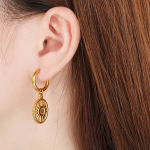 Detailed close-up of 18K gold plated oval earrings with moon and sun pendant design