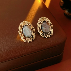 Detail of vintage oval resin earrings with gold metal frame on brown leather jewelry box