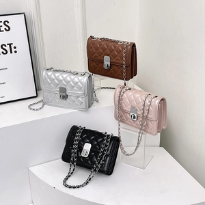 Quilted chain shoulder bag in multiple colors displayed on white geometric platforms