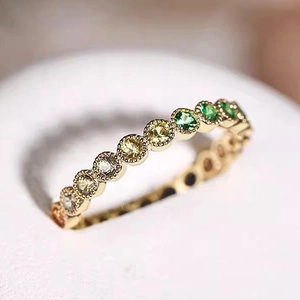 Detail of gold eternity ring with multi-colored gemstones and delicate milgrain edges