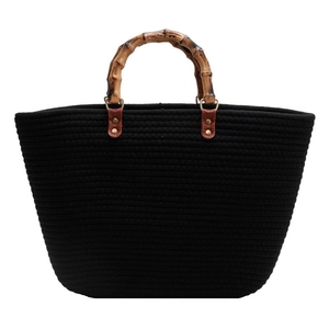Black woven tote bag with natural bamboo handles and reinforced leather patches