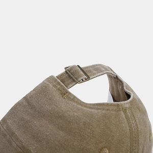 Detail of adjustable brass buckle and stitched strap on khaki vintage washed baseball cap