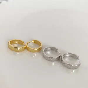 Macro shot of 925 silver hoop earrings with geometric quilted pattern in gold and silver