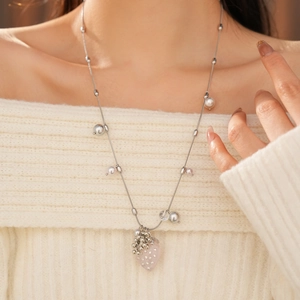 Detailed view of silver necklace with pink heart pendant and pearls on a white sweater