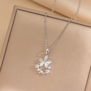 Elegant silver flower pendant necklace with white opal, zircons, and pearl on jewelry box
