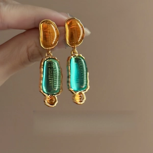 Detail of vintage earrings with amber and green resin in gold metallic frames