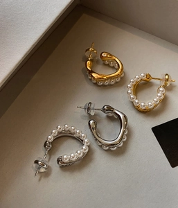 Detailed view of elegant gold and silver pearl hoop earrings in a gray jewelry box