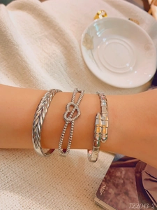 Detailed view of silver minimalist stacked bracelet set featuring wheat and heart knot textures