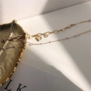 Golden double-layer bracelet with paperclip chain, heart charm and pearl accents