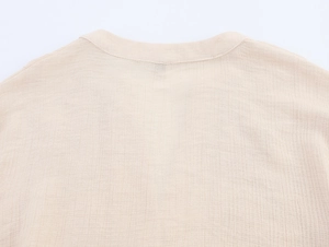 Detailed macro view of the beige cotton linen fabric and hollow embroidery on the neckline