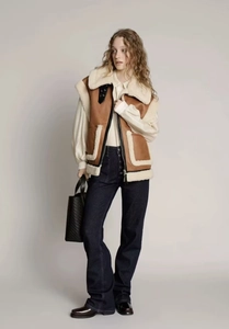 Détail du gilet en peau de mouton marron et beige avec fermeture éclair et poches