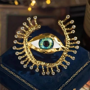 Detailed close-up of golden evil eye brooch with blue iris and sparkling crystals
