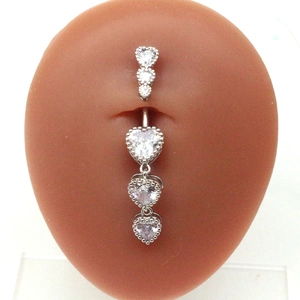 Macro detail of silver navel ring with triple dangling heart-shaped cubic zirconia stones