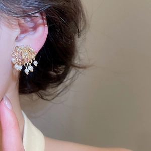 Close-up detail of elegant 18k gold-plated firework earrings with pearls and crystals.