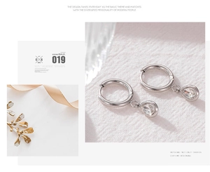 Detail of silver hoop earrings featuring clear water drop zircon pendants on fabric