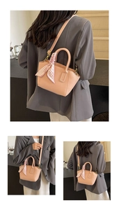 Detail showing pink pebble leather bucket bag with silk scarf on handle and crossbody strap