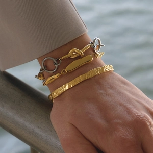 Three-piece gold and silver stackable bracelets including a textured cuff and link chains