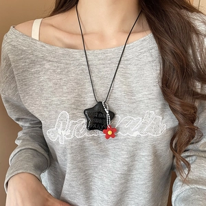 Dettaglio collana con stella nera e fiore rosso con scritta Mind Your Own Business