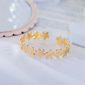 Detailed view of the gold-plated daisy flower pattern on the polished open bangle