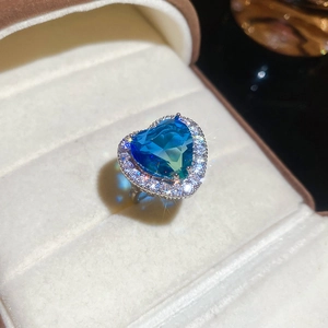 Macro shot of a heart-shaped blue zircon ring with a silver-tone band in a soft jewelry box