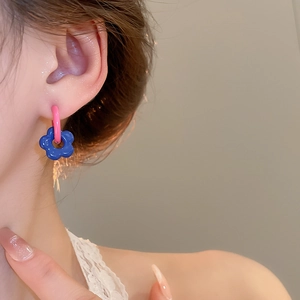 Detailed view of pink ring and blue flower earrings on model with glossy enamel finish
