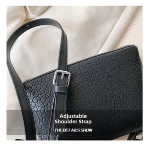 Detail of adjustable black leather strap with silver buckle on fashion handbag