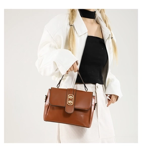 Detail view of caramel brown crossbody bag with gold buckle and smooth leather texture