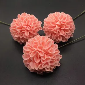 Three pink artificial dahlia flowers with green stems on dark grey textured background