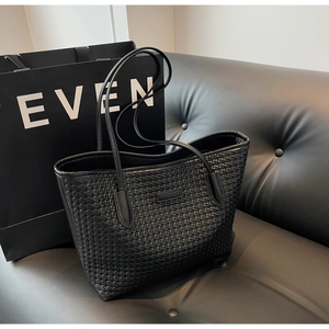 Close-up of black woven tote bag texture with elegant leather grain and brand logo