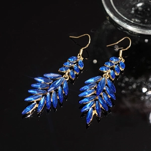 Elegant gold-tone drop earrings with navy blue crystals and leaf tassel on reflective black base