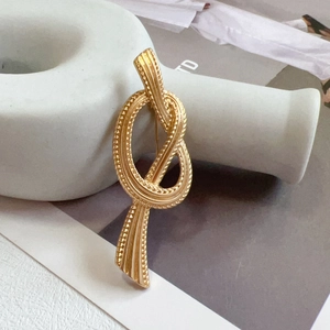 Detailed view of a gold vintage knot brooch placed on a white ceramic ornament