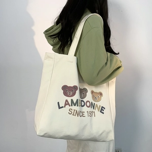 Detail of large canvas tote bag featuring cute cartoon bear embroidery and shoulder strap
