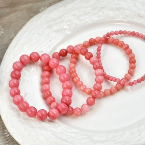 Detail of four pink rhodochrosite beaded bracelets with natural textures in various bead sizes