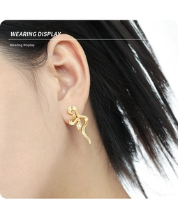 Wearing display of gold snake-shaped stud earrings with sparkling zircon inlay