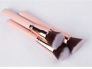 Detailed view of dense round head makeup brushes with pink handles and rose gold ferrules