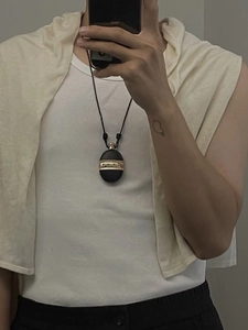 Detailed view of the oval black pendant with golden metal inlay and woven cord strap