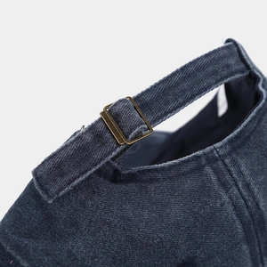 Macro detail of adjustable bronze metal buckle and denim strap on a navy baseball cap