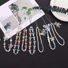Macro shot of colorful beaded phone straps with butterfly and bear charms on black surface