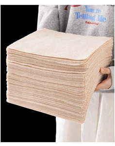 Close-up of hand holding a stack of beige microfiber dishcloths for kitchen cleaning