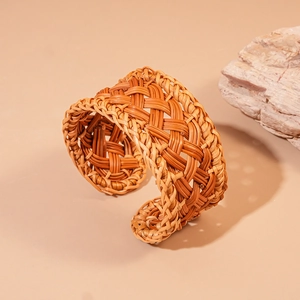 Detailed view of handmade woven rattan cuff bracelet on natural stone background
