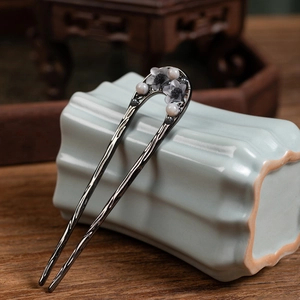 Detail of silver U-shaped hair fork with white flower and pearls on ceramic background