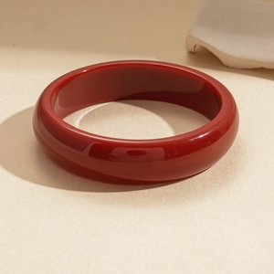 Close-up of polished dark red resin round bangle with smooth glossy finish on stone