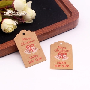 Close-up of brown kraft paper Christmas tags with red bell print and festive greetings